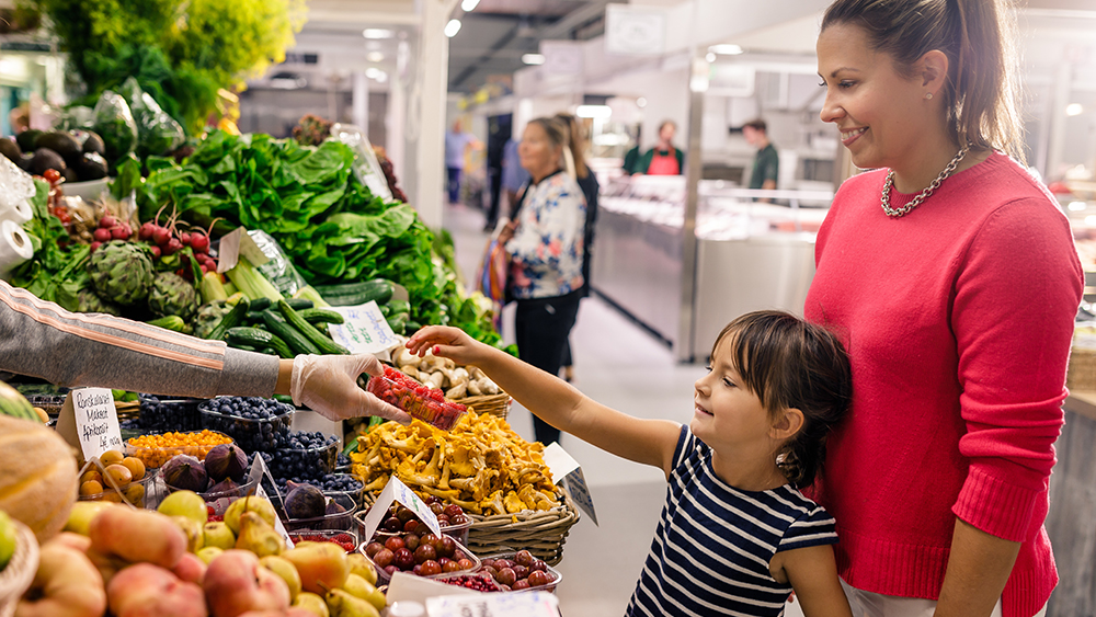A photo of a mother and a child shopping berries and vegetables.